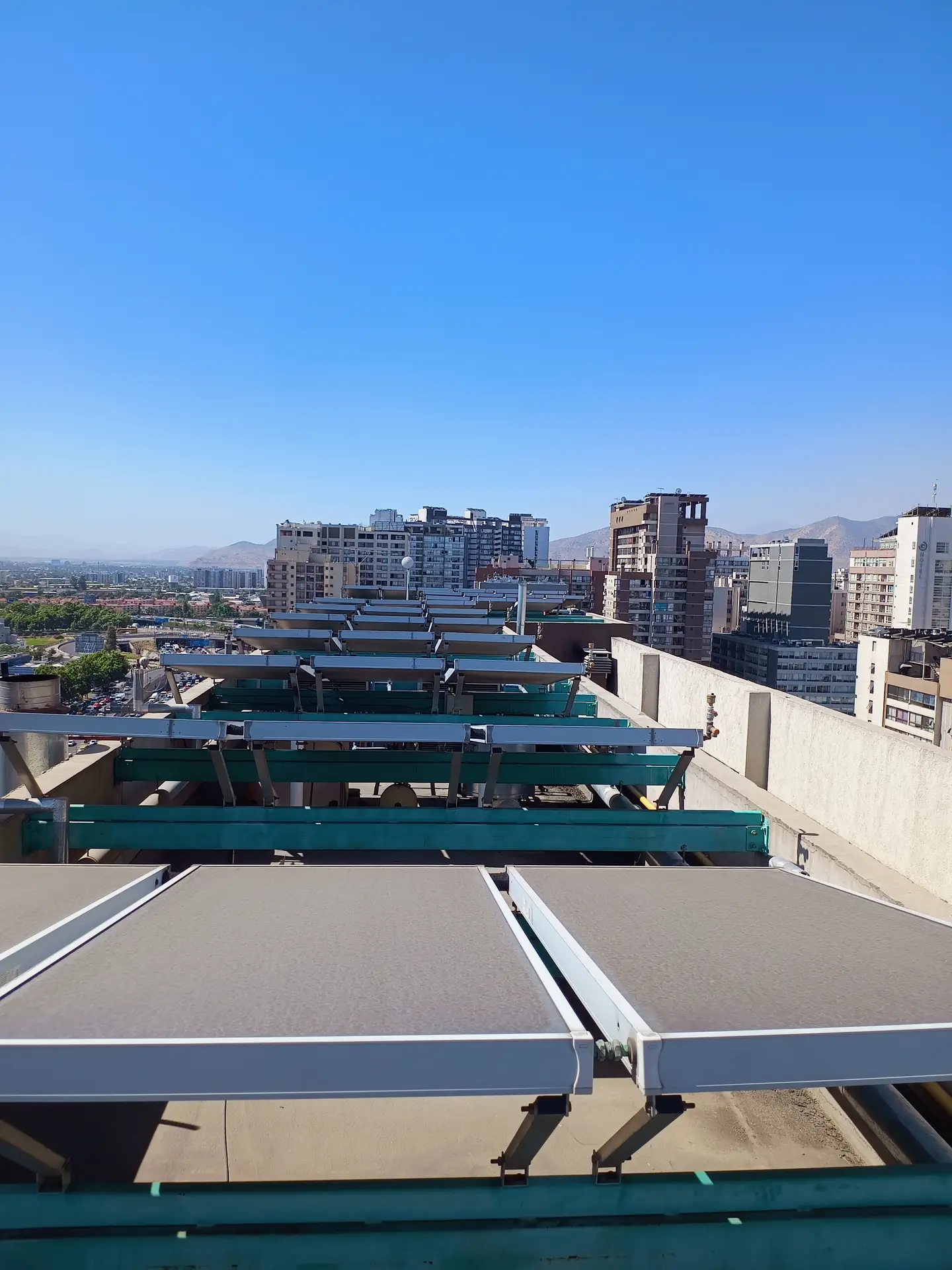 Colectores solares térmicos en la azotea de un edificio, con Santiago y la cordillera de fondo